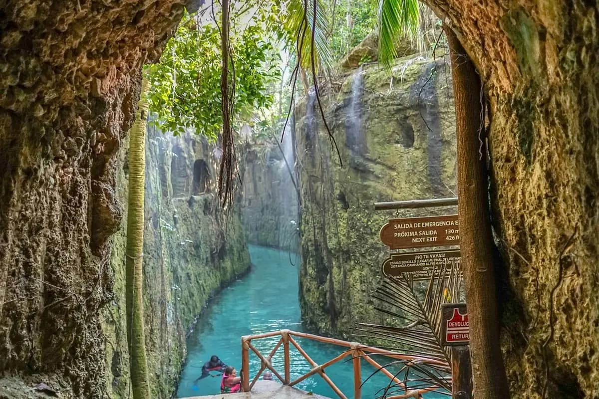 A turquoise cenote canyon at Xcaret with a wooden walkway