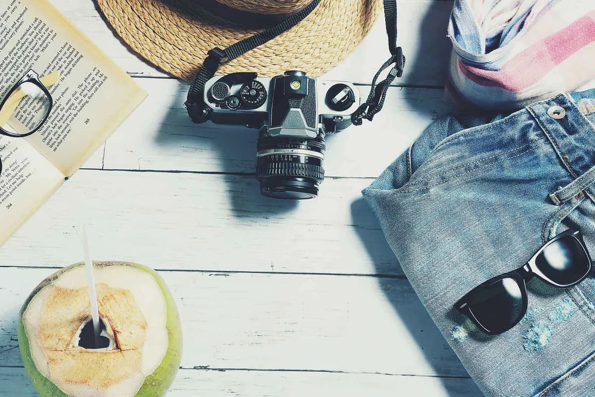A camera, sun hat and sunglasses laid out for a trip