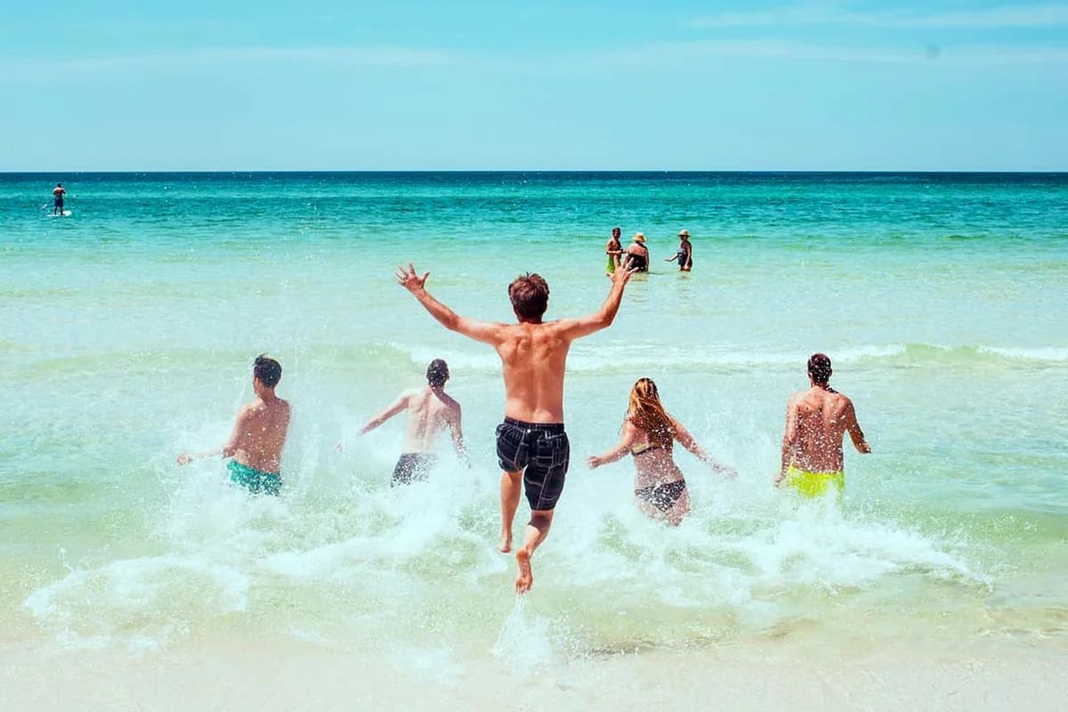 Friends running into turquoise ocean water together